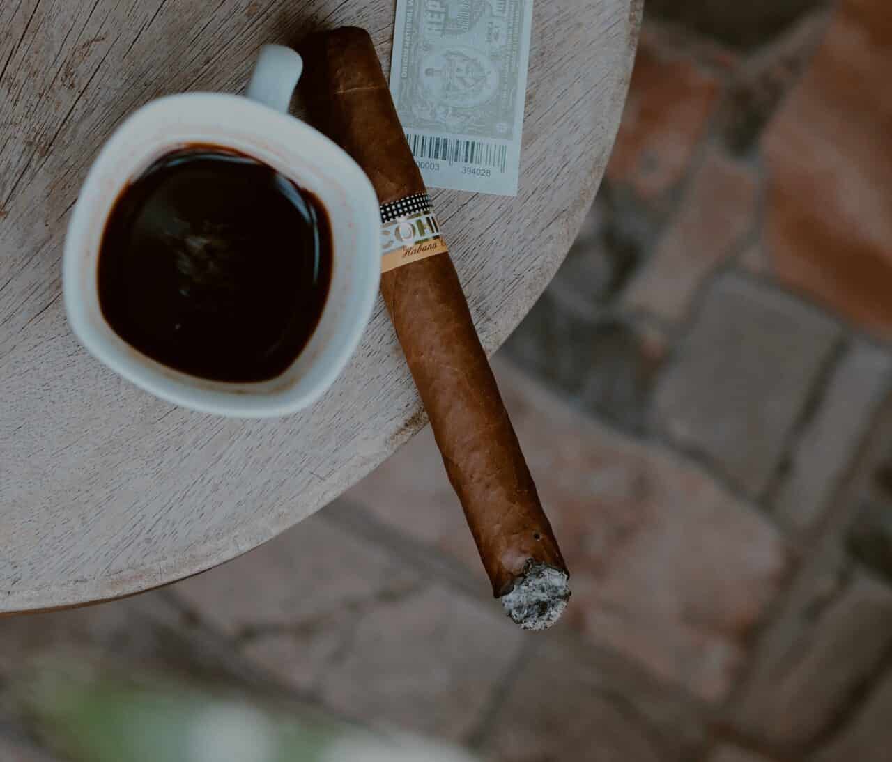 black coffee and a cigar on a patio table