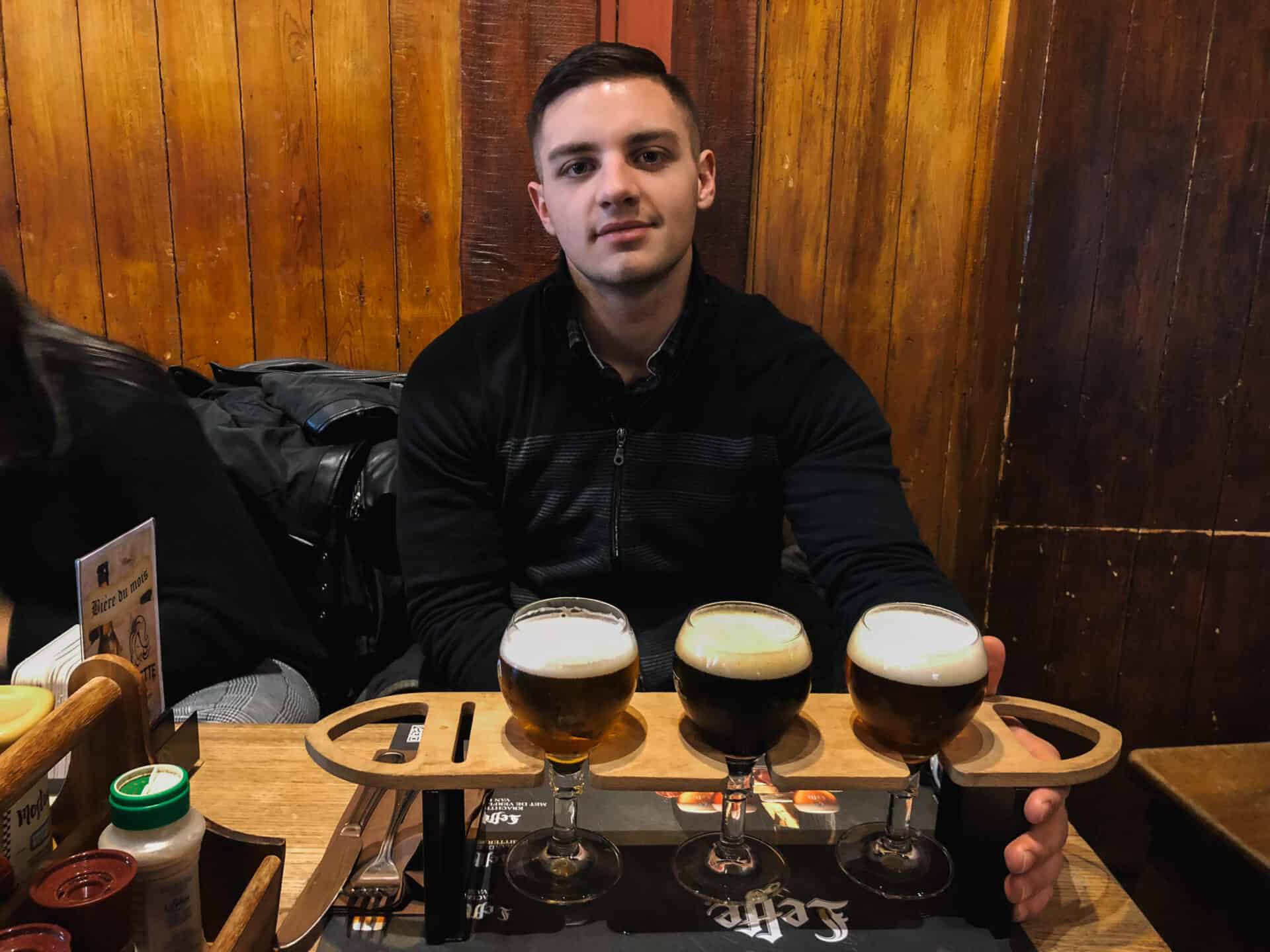 American man with a flight of Belgian beers in Brussels restaurant