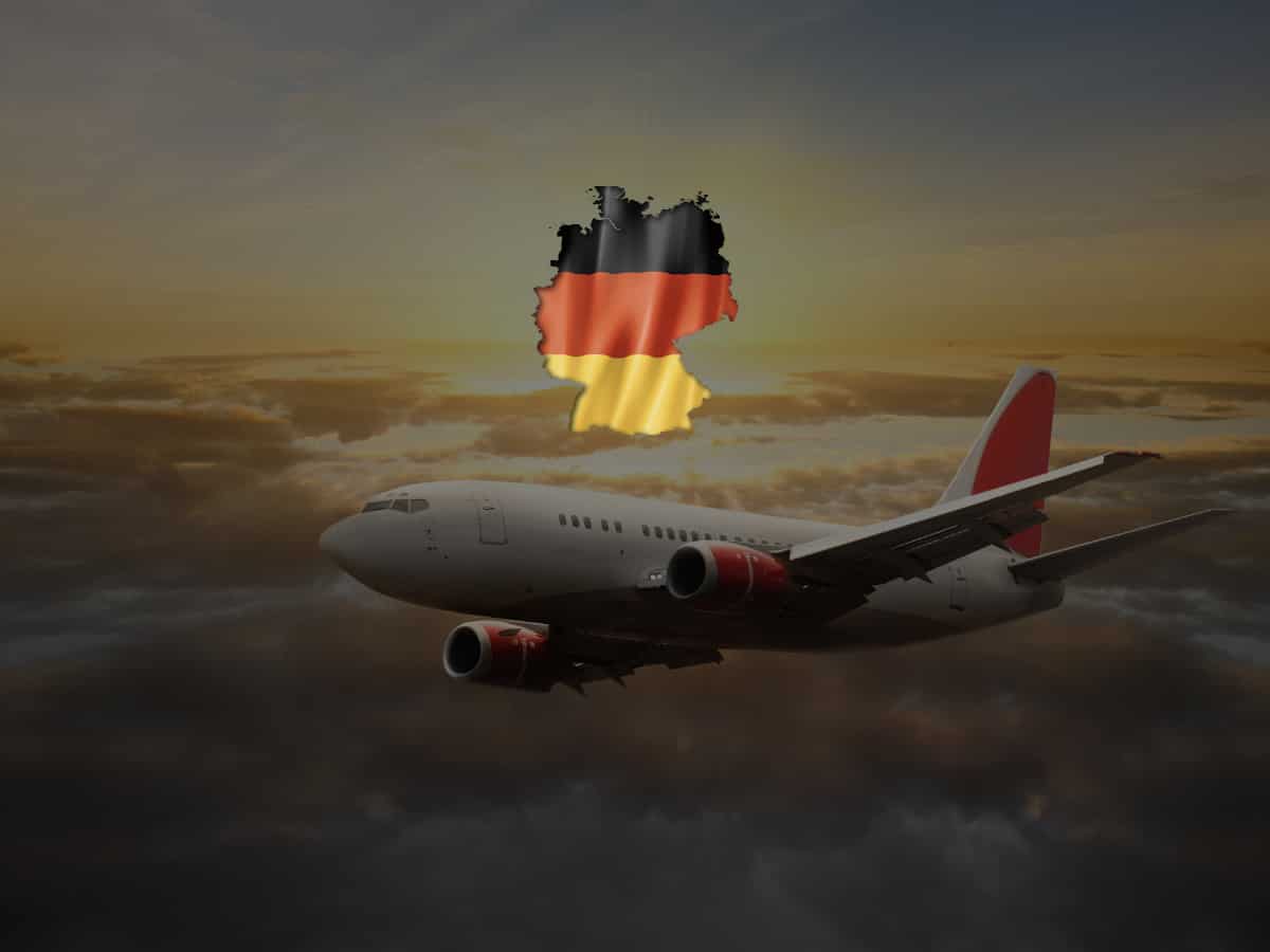 white airplane with German flag flying over a sunset