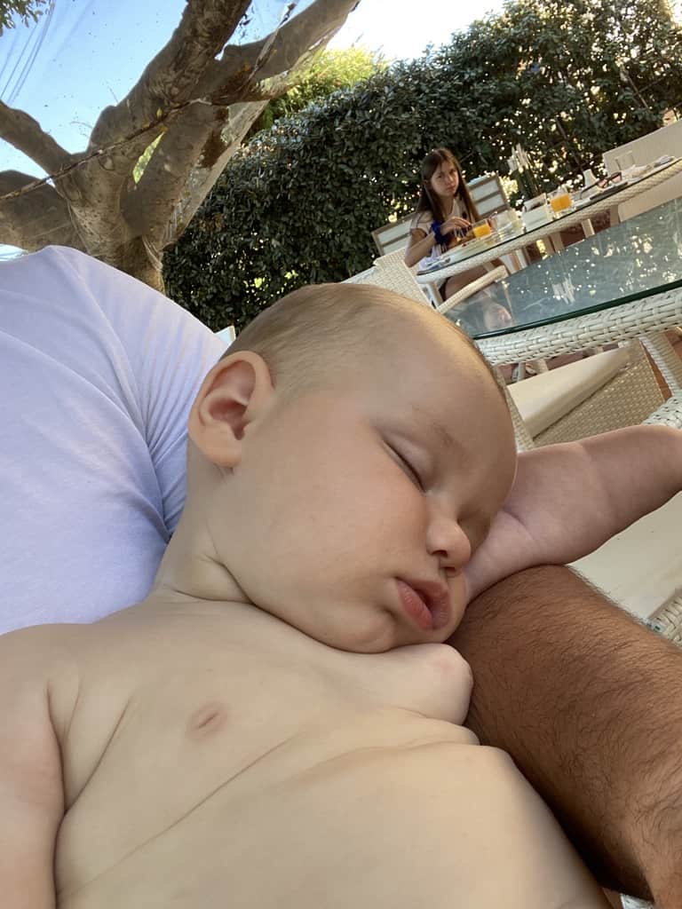 shirtless baby sleeping on dads lap