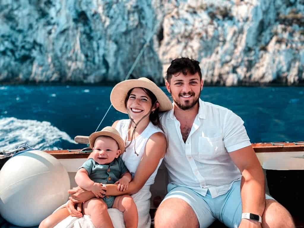 Man, woman, and baby smiling on a boat in dark blue waters