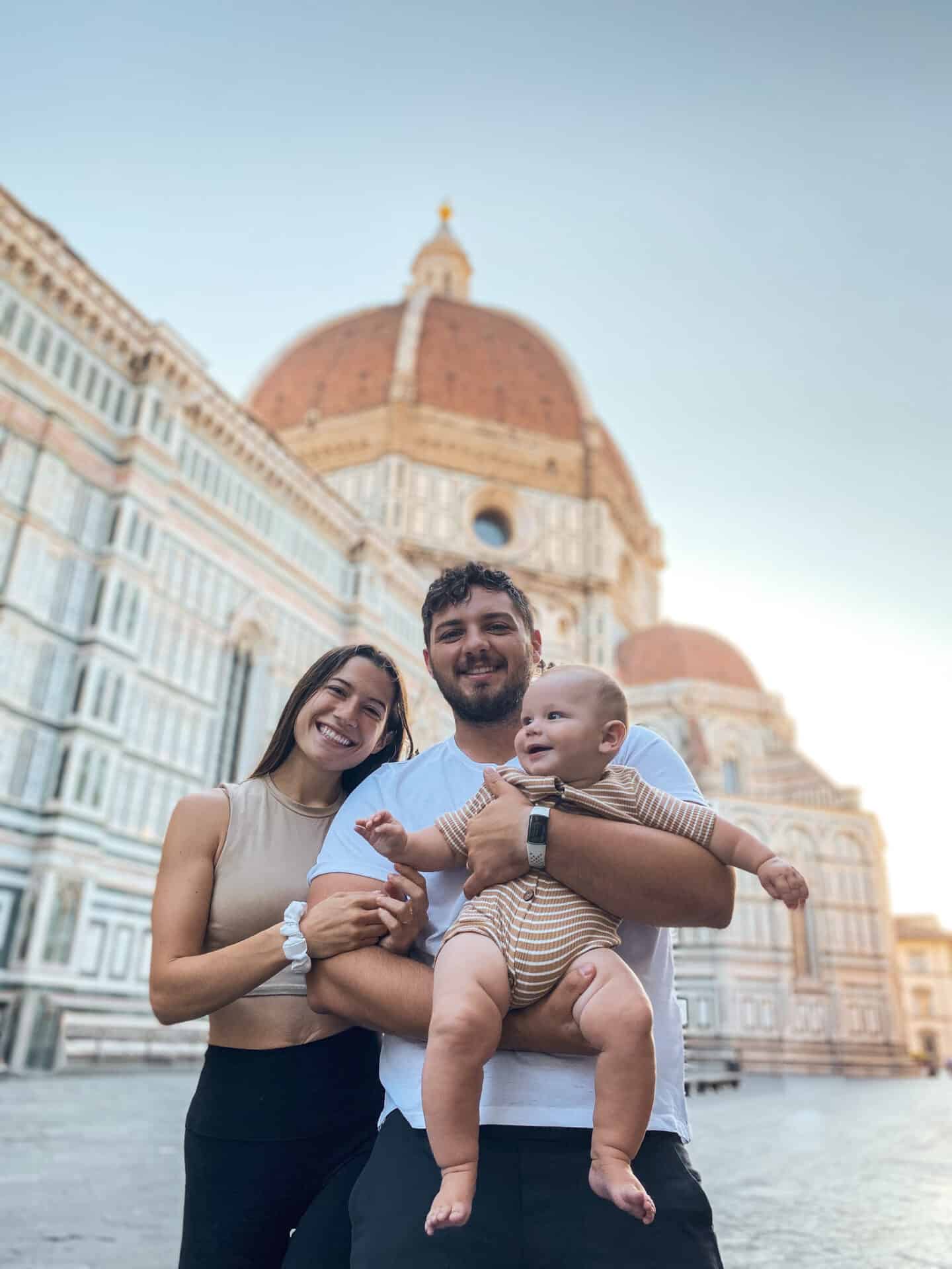 Sweet Catholic Couple with baby in arms smiling in front of Florence's Dome