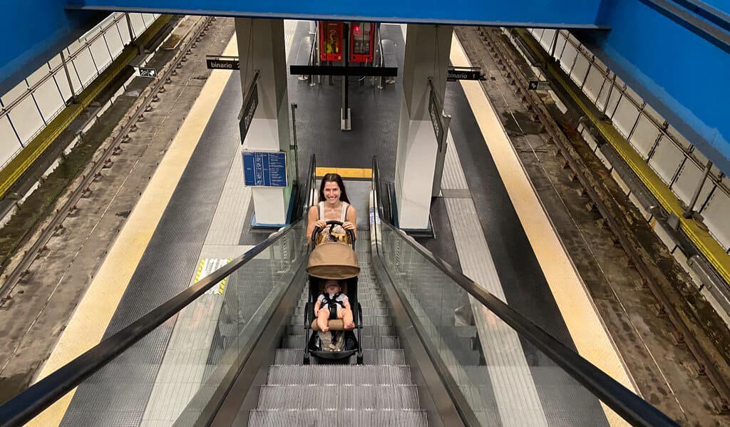 woman pushing a stroller up a european escalator