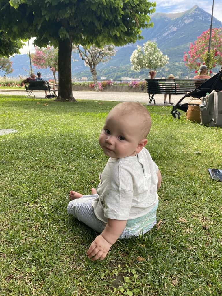 six month old baby sitting on green grass