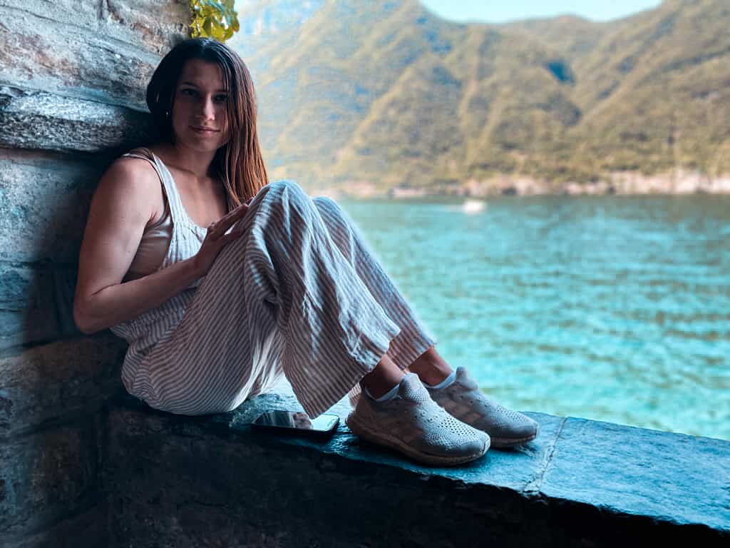 woman sitting on a ledge overlooking a lake