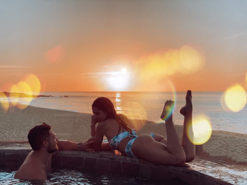 man and woman romantically in a hot tub on the beach during sunrise