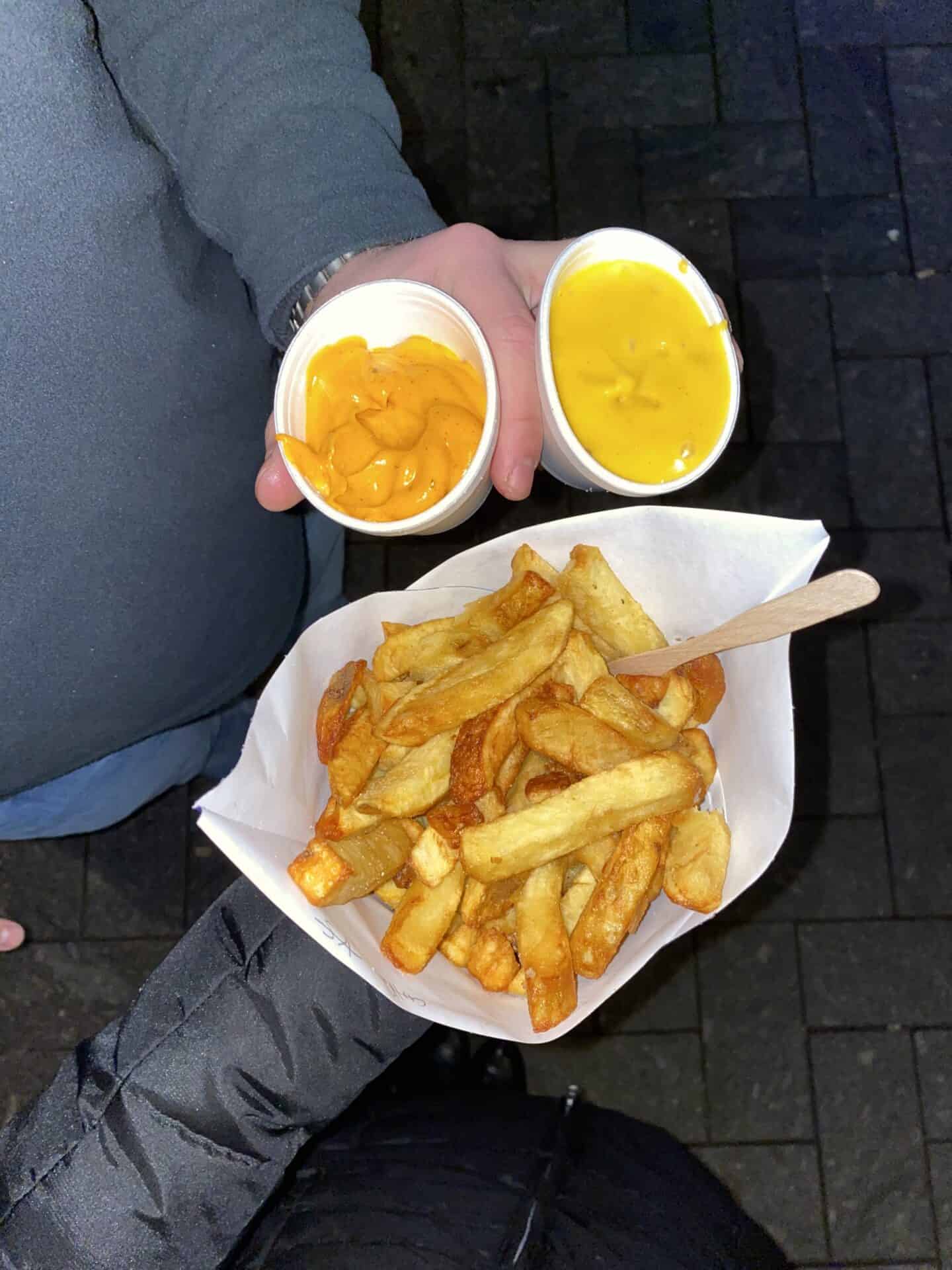 Cone of French fries with cheese and mustard