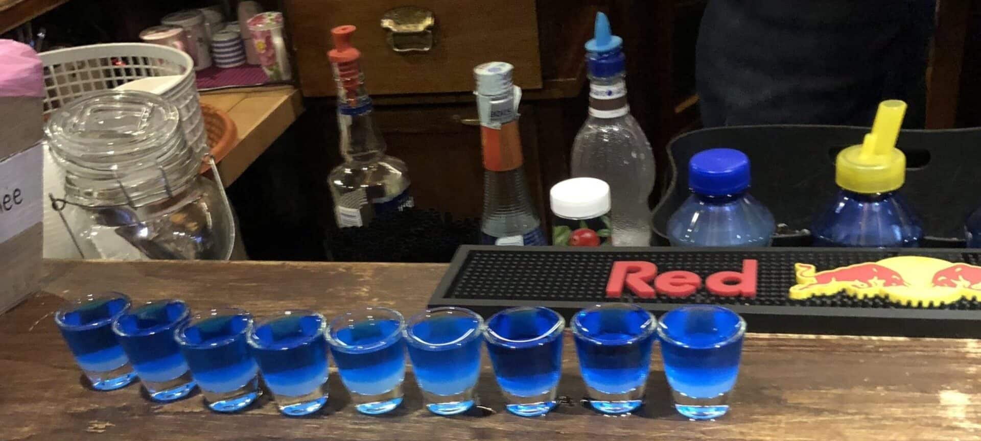 Blue shots of liquor being served in a rustic bar in Urbino