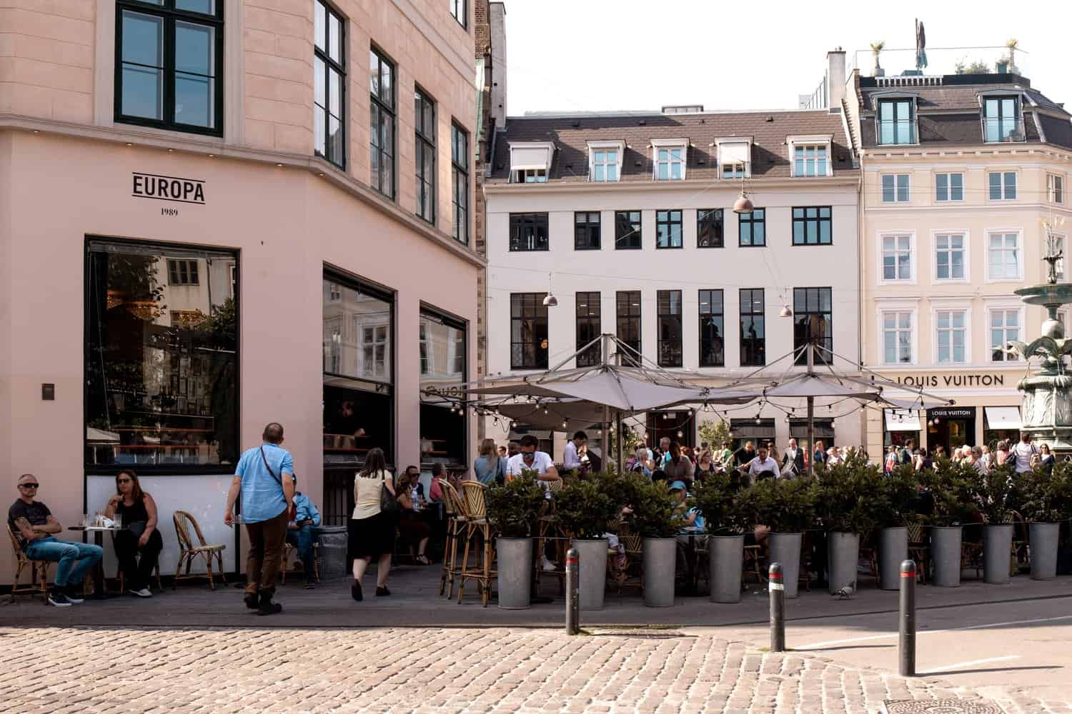 cute european cafe building with people drinking coffee on outside tables