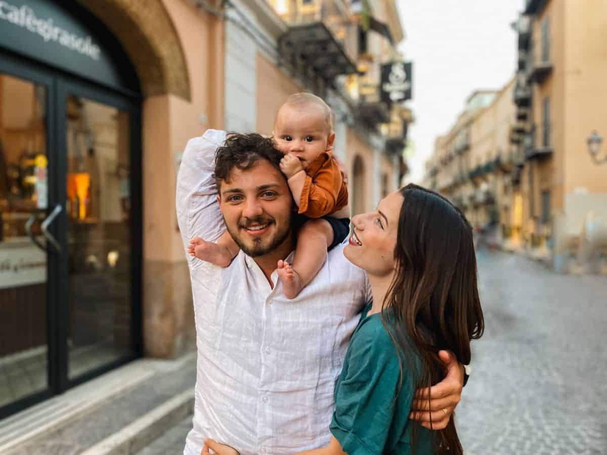 husband and wife adoring eachother with baby son sitting on dads head