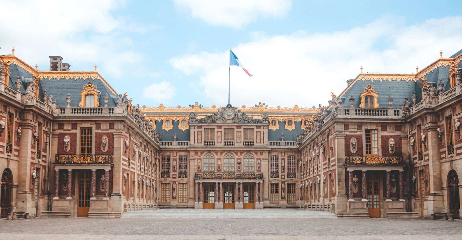 French Flag waving above the Palace of Versailles in Paris