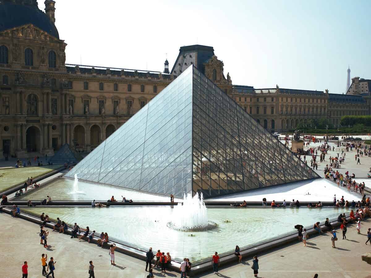 people walking around glass pyramid louvre landmark
