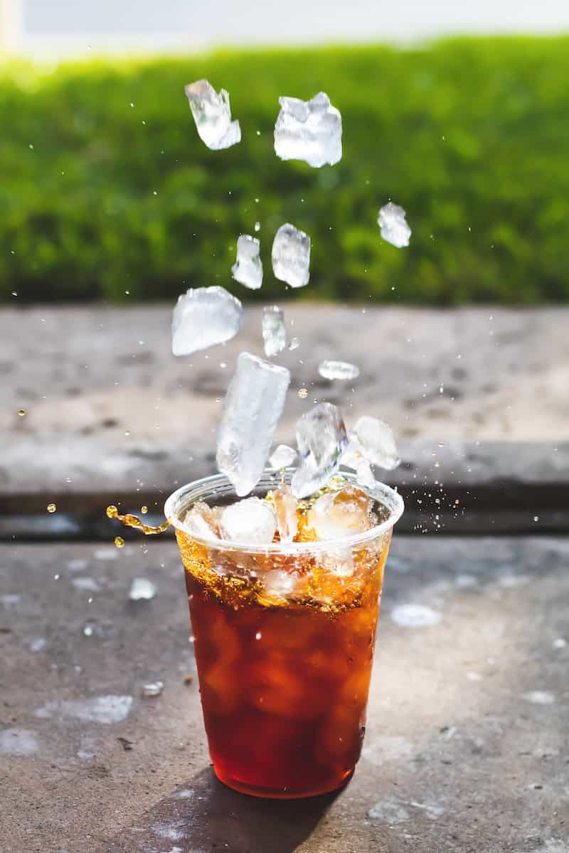 macro photography of dropping ice cube in iced coffee