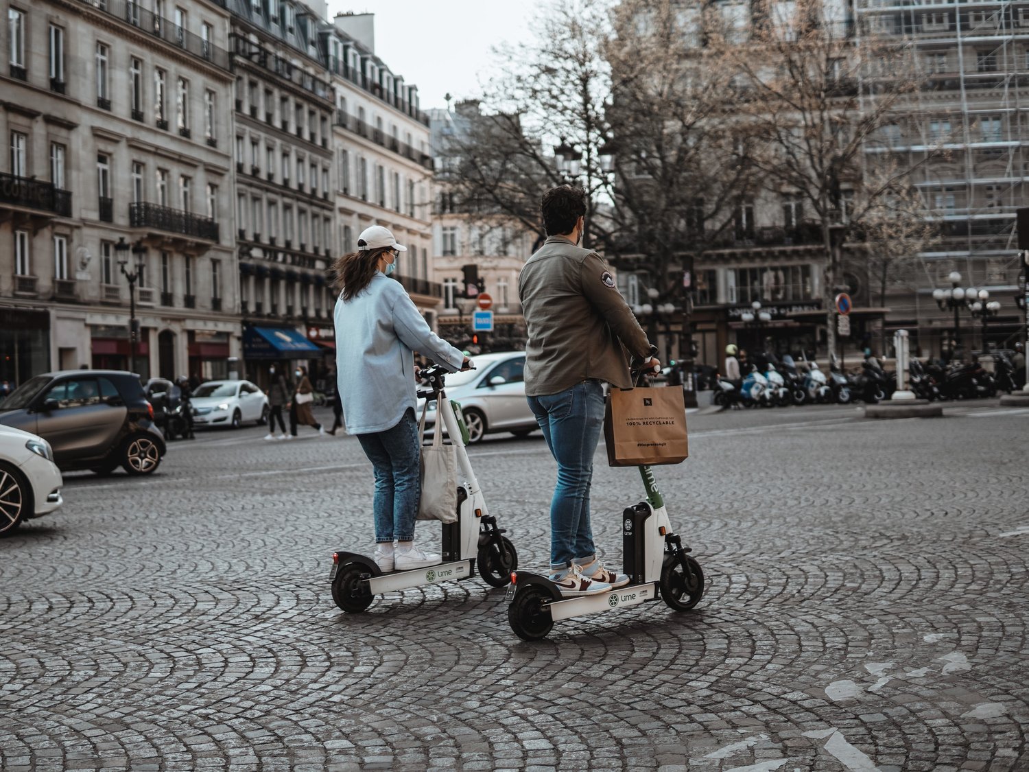 German man and woman riding white electric scooters