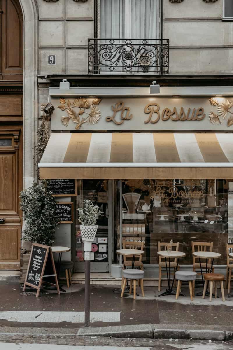 Cute street side cafe in Paris with brown wooden table and chairs