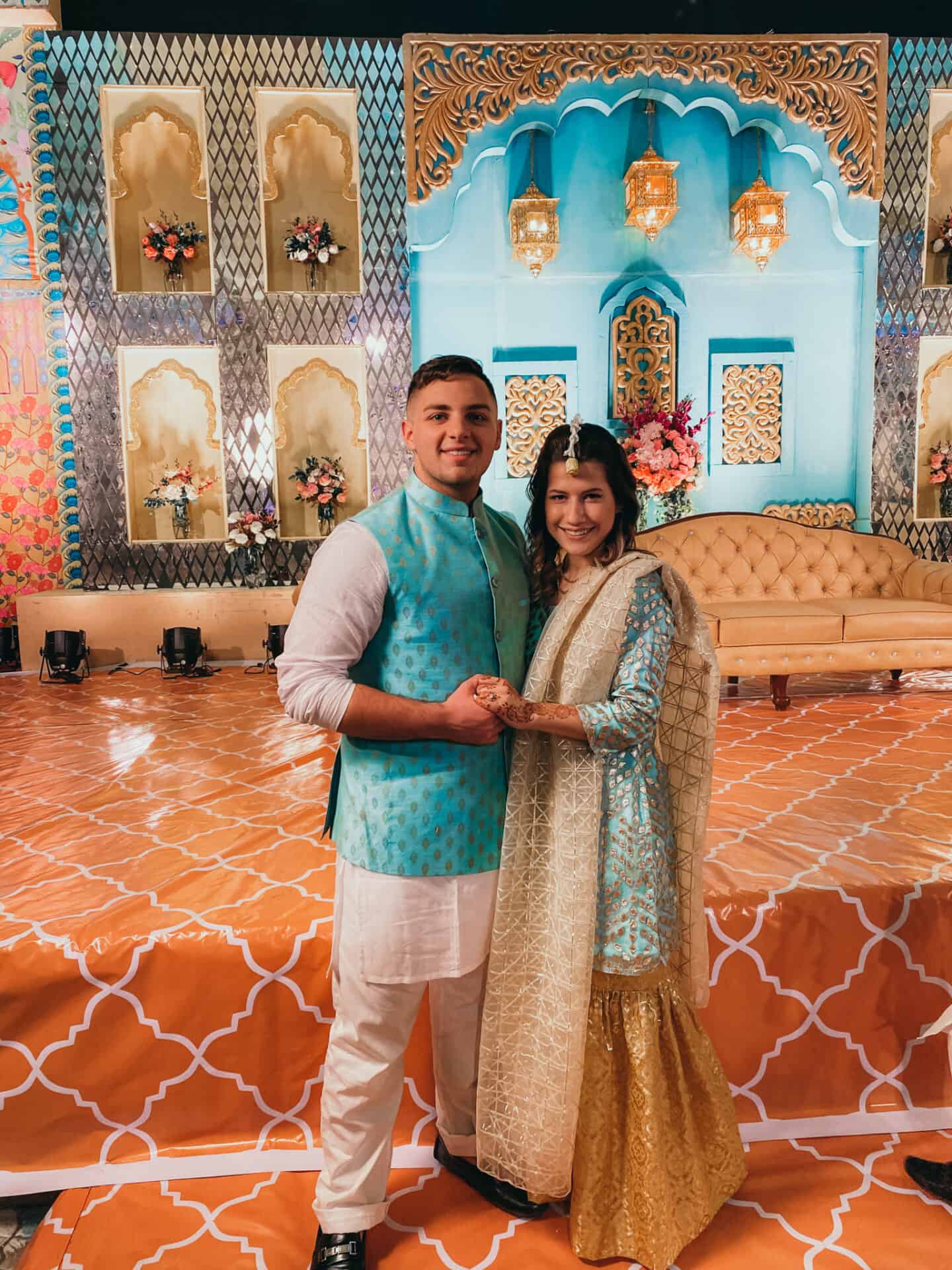 man and women in blue bangladeshi costumes in front of elaborate wedding stage