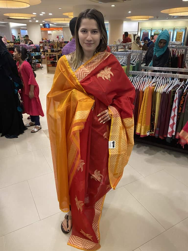american woman trying on a red and orange saree in bangladesh store