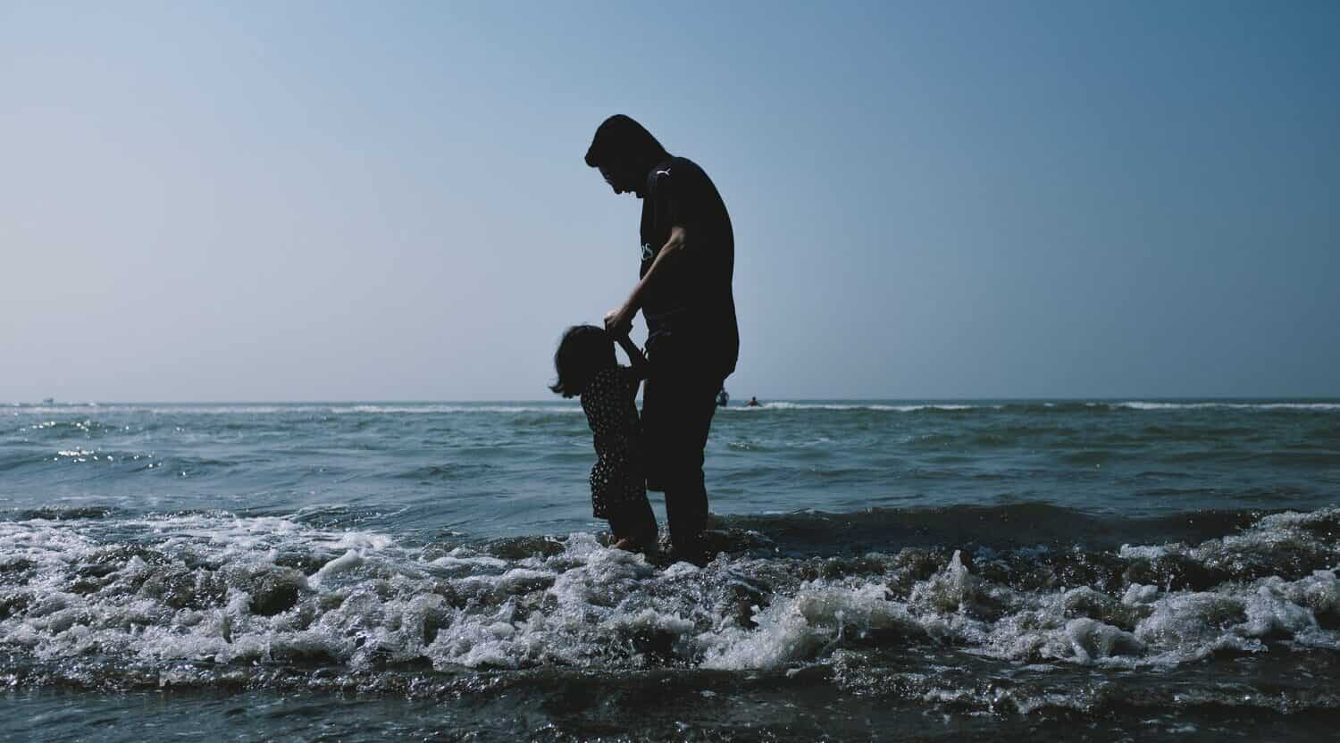 silhuette of father playing with young daughter in the ocean of cox's bazar