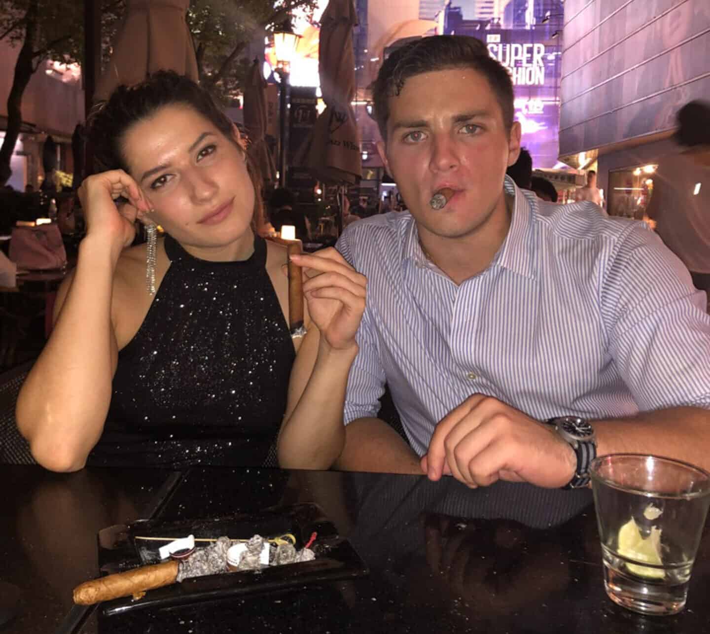 woman in sparking black dress and man in button down smoking cigars in shanghai night club