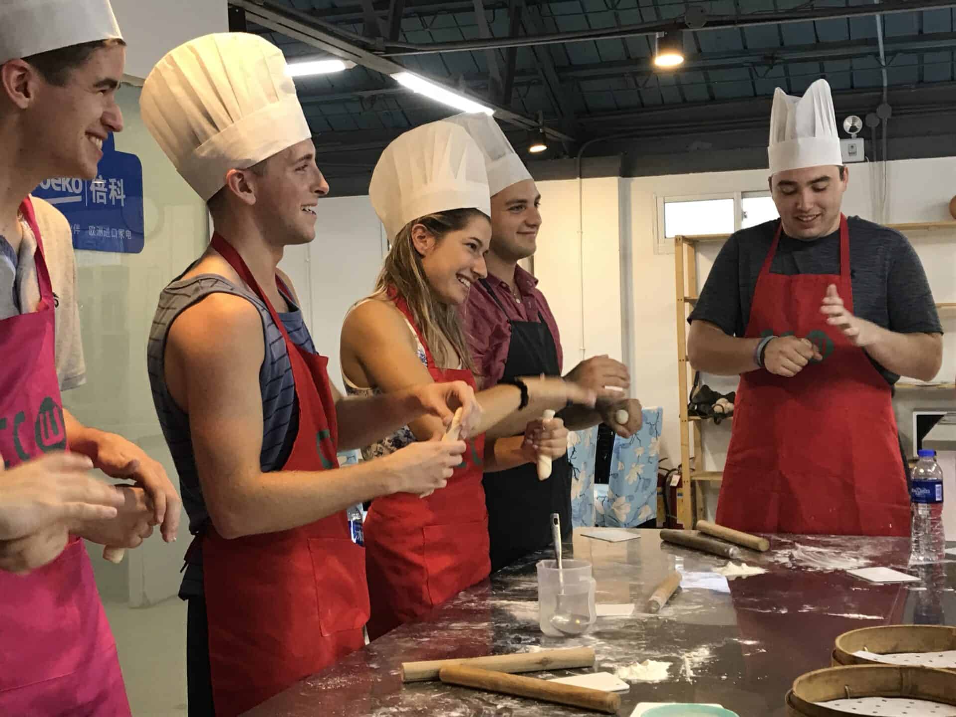 students in chef hats making dumplings in china