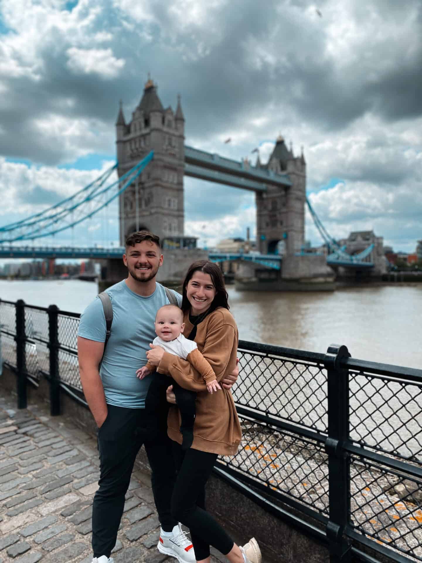 American family with baby posing for picture in front of Tower Bridge in London