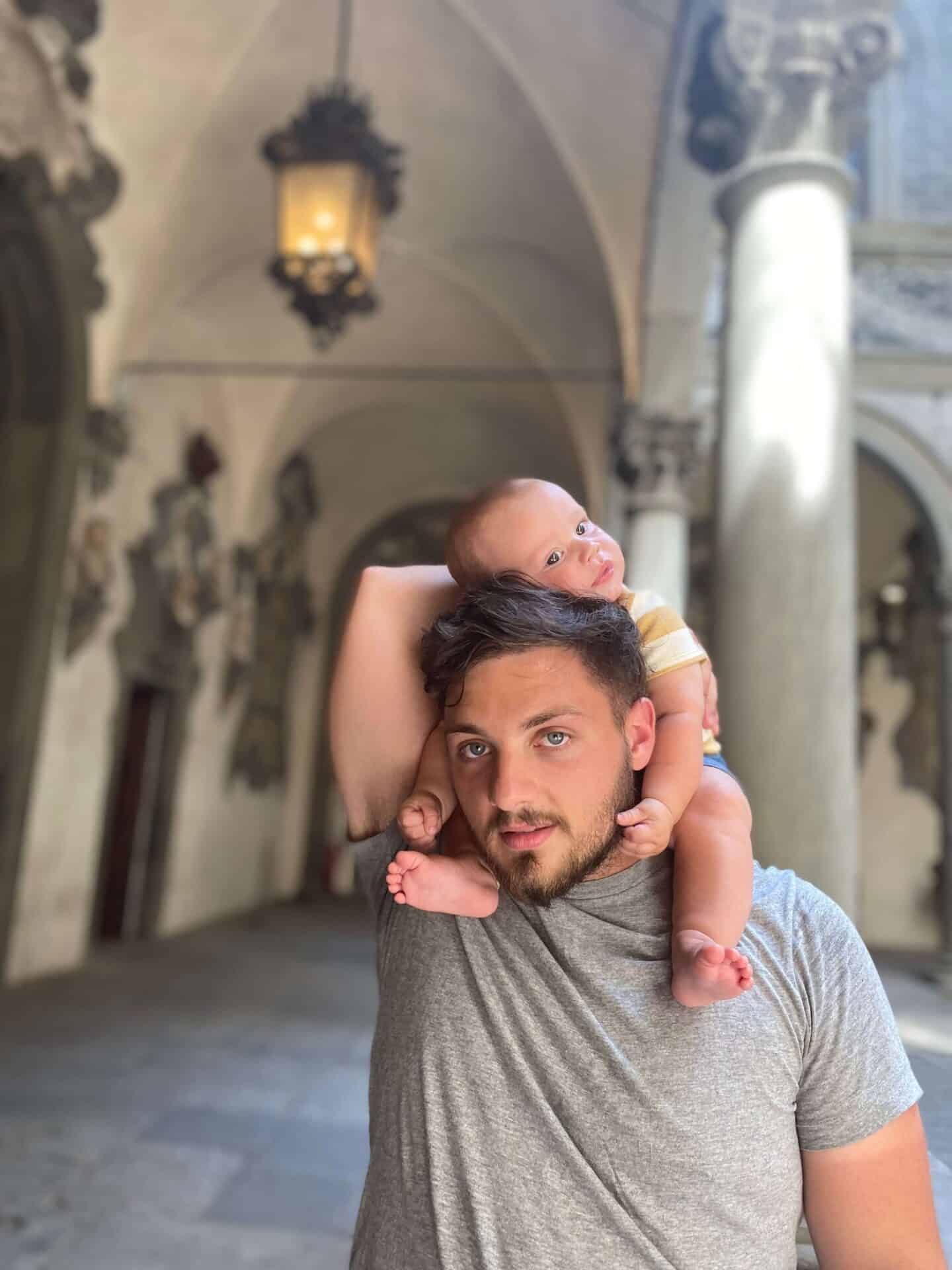 Father with adorable baby son on his shoulders at Pitti Palace in Florence