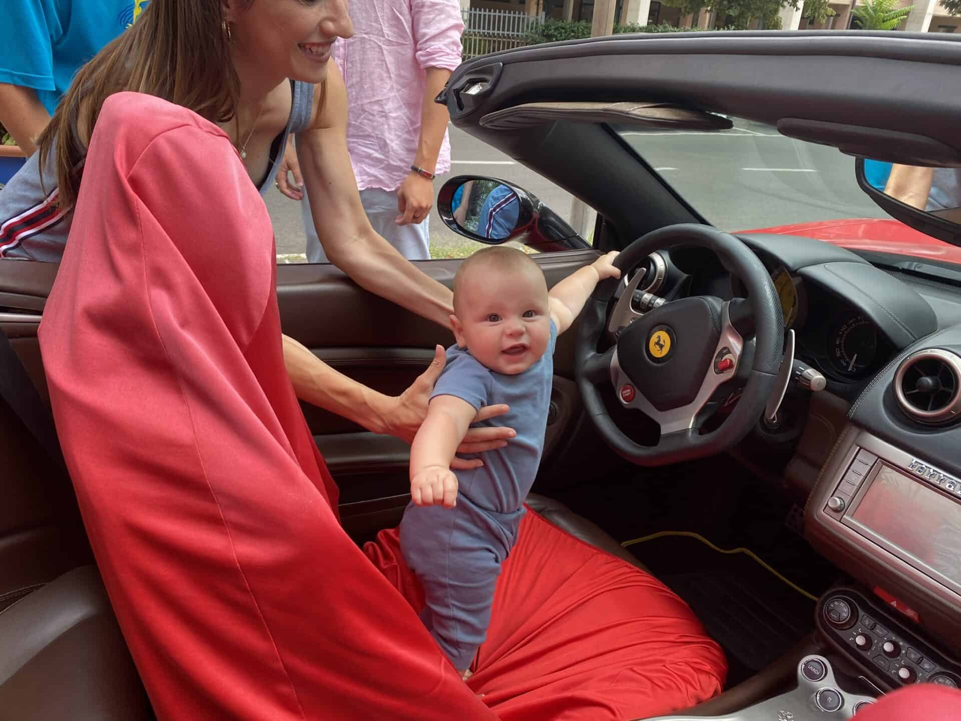 six month old baby driving a red ferrari