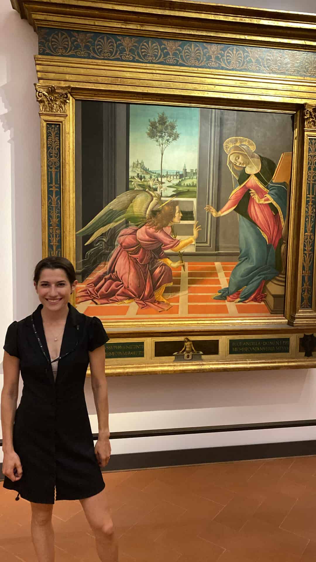 woman smiling in front of renaissance painting of The Annunciation of Christ