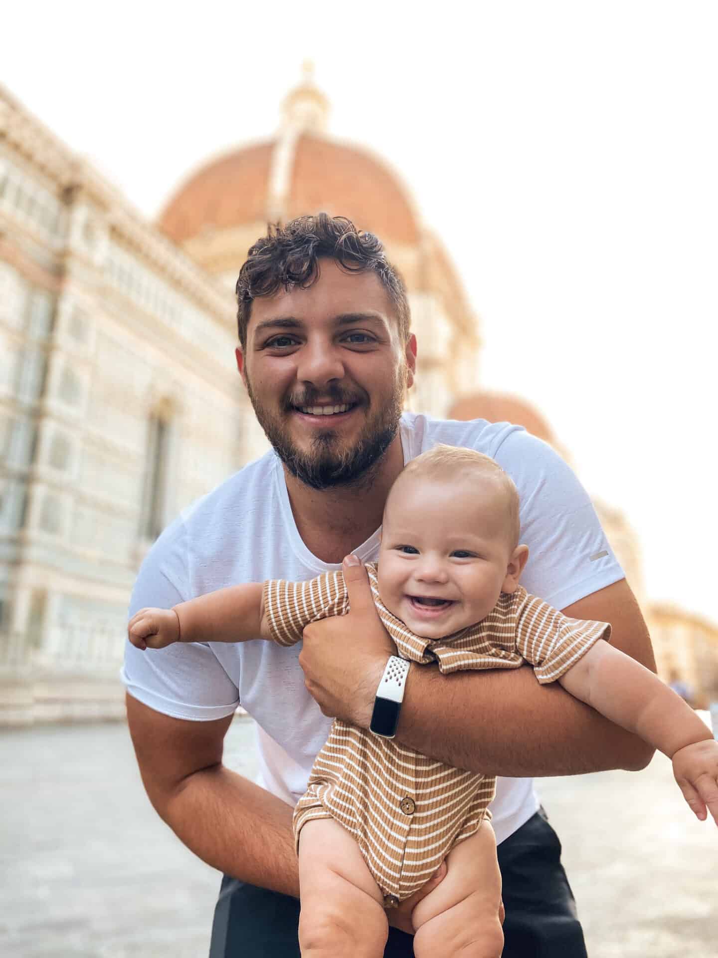 adorable father and baby in arms smiling in front of Florence's Dome