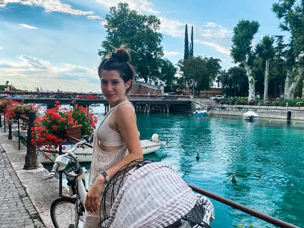 female model sitting on a bike on a bridge by Lake Garda blue canal