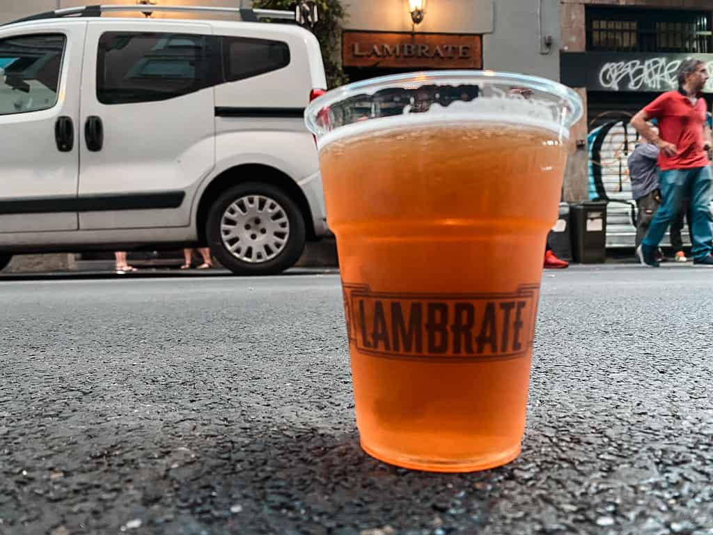 Clear beer in cup that reads Lambrate in Milan Italy