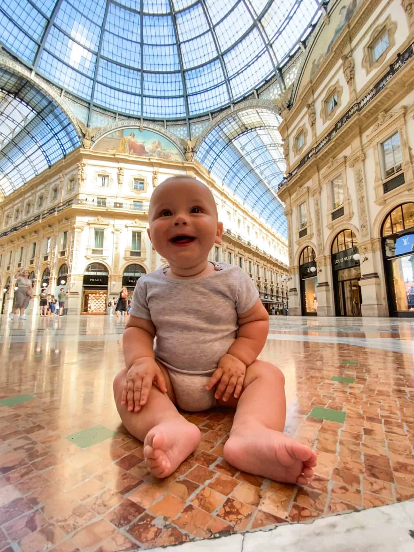 Adorable 6 month old baby smiling on the marble floor at Galleria early in the morning in milan