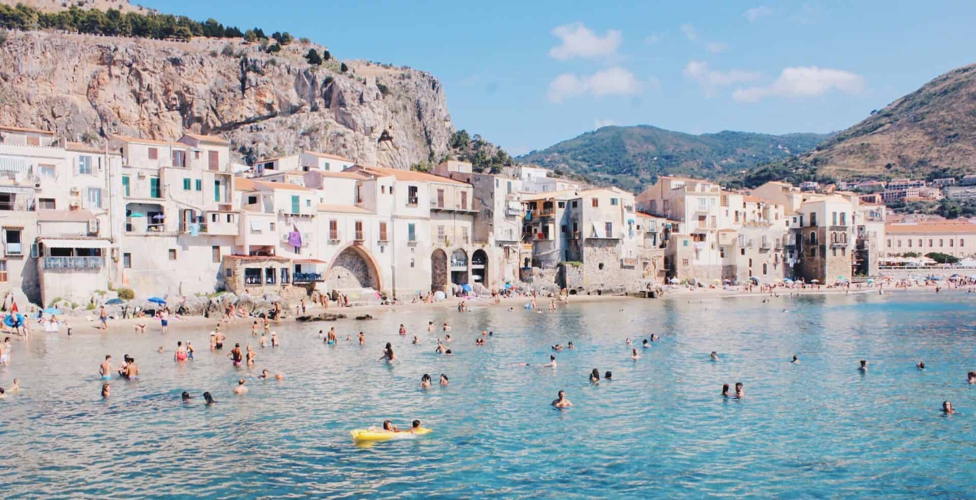 Tourists swimming in clear waters of the Mediterranean Sea in Sicily
