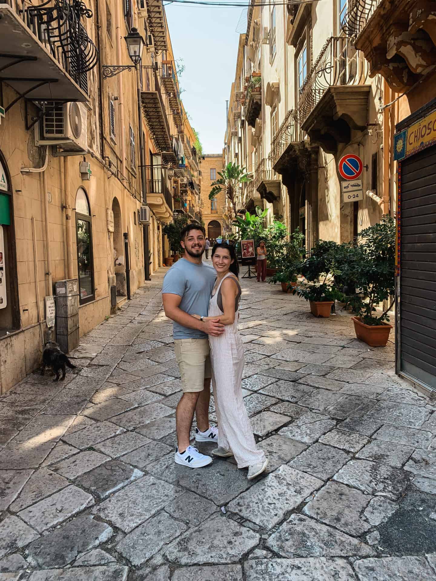 American couple standing in quaint alleyway with trees in Palermo