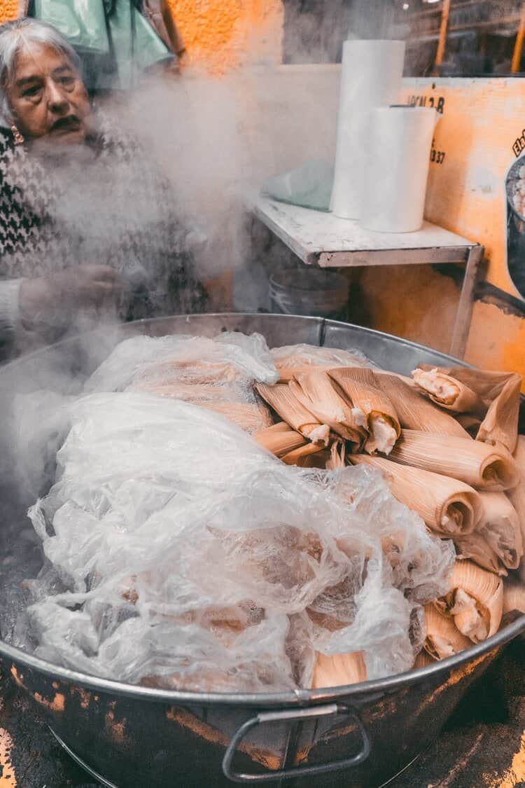 Elderly Mexican woman cooking tamales in a large pot