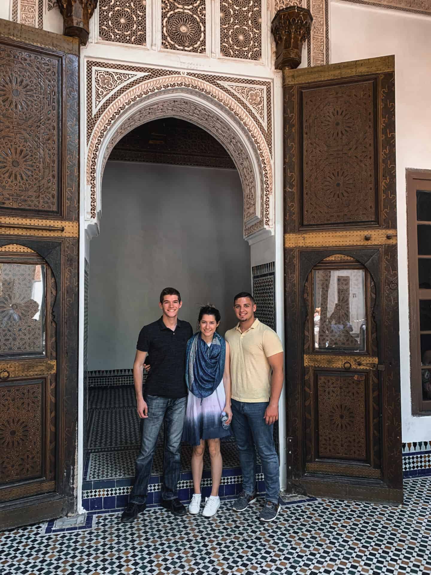 3 tourists standing in the doorway of Elaborate mosaic arch in Museum Marrakech Morocco