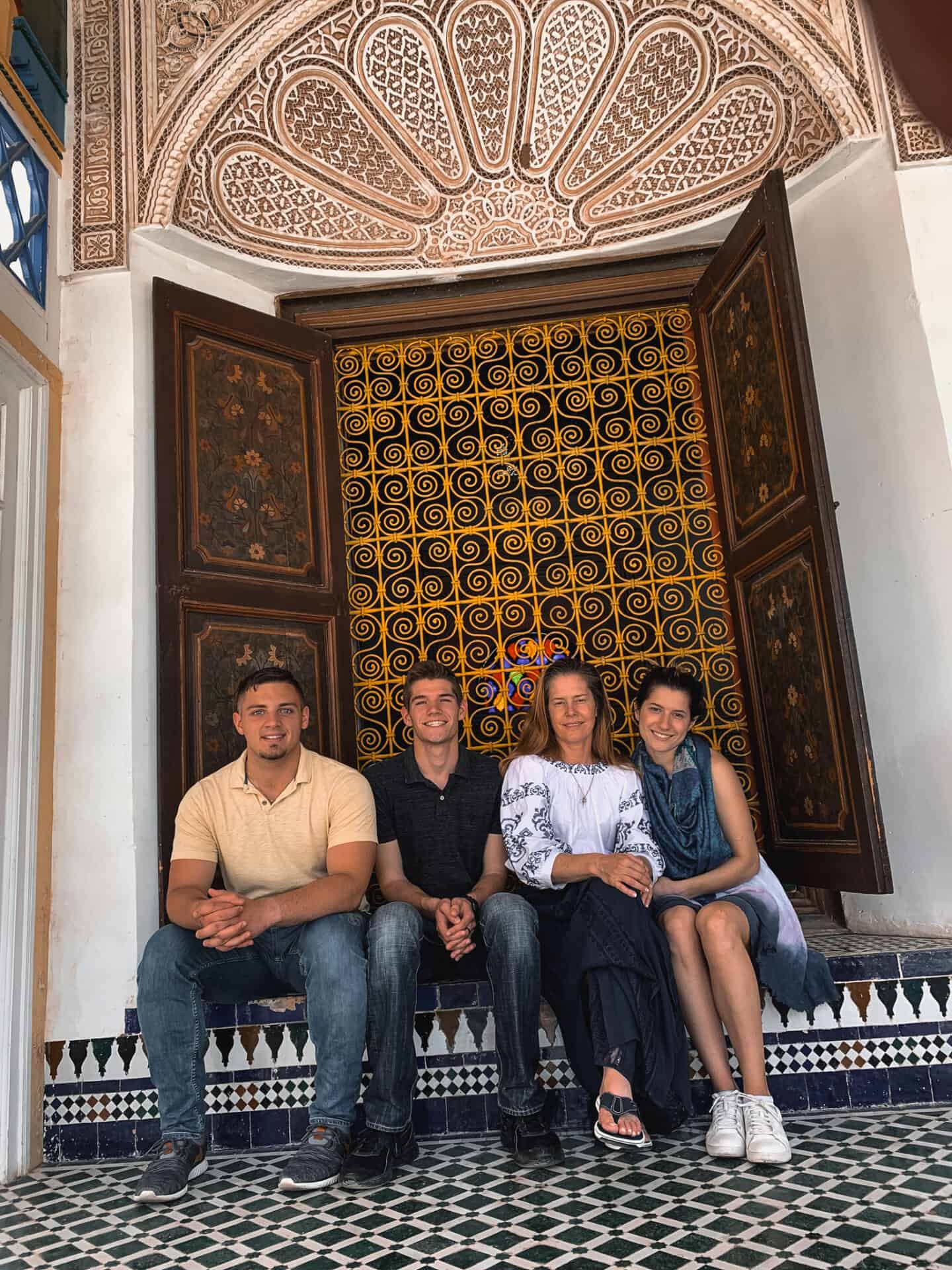 four tourists sitting by a Golden Window in Museum Marrakech Morocco