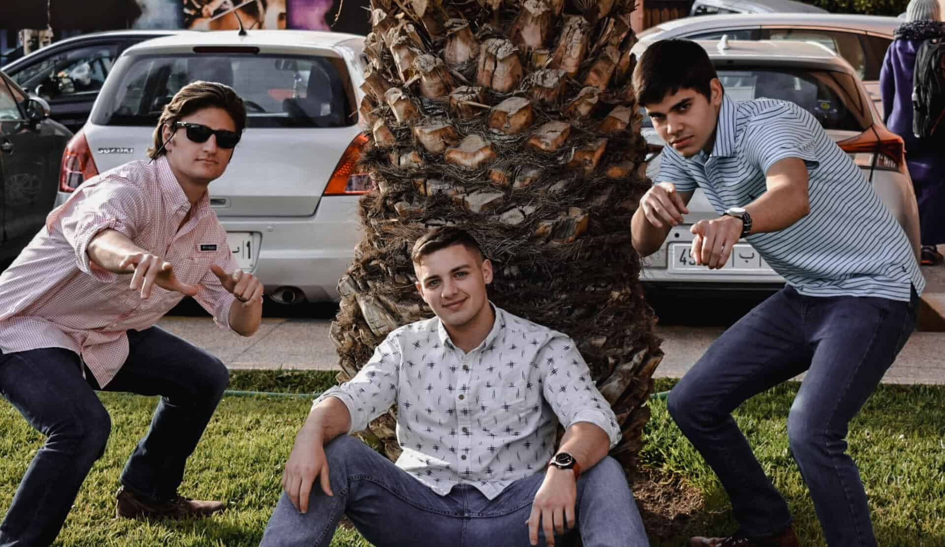 young American men sitting under palm tree in Marrakech Morocco