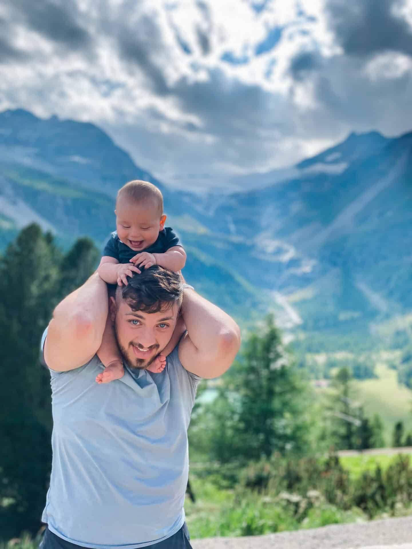 Dad with a baby on shoulders overlooking the Swiss Alps on Bernina Express