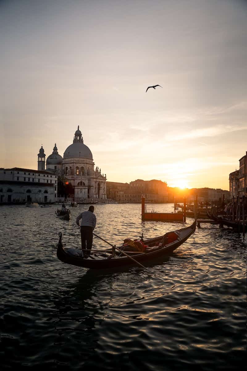 people riding on gondola in Venice on river during sunset