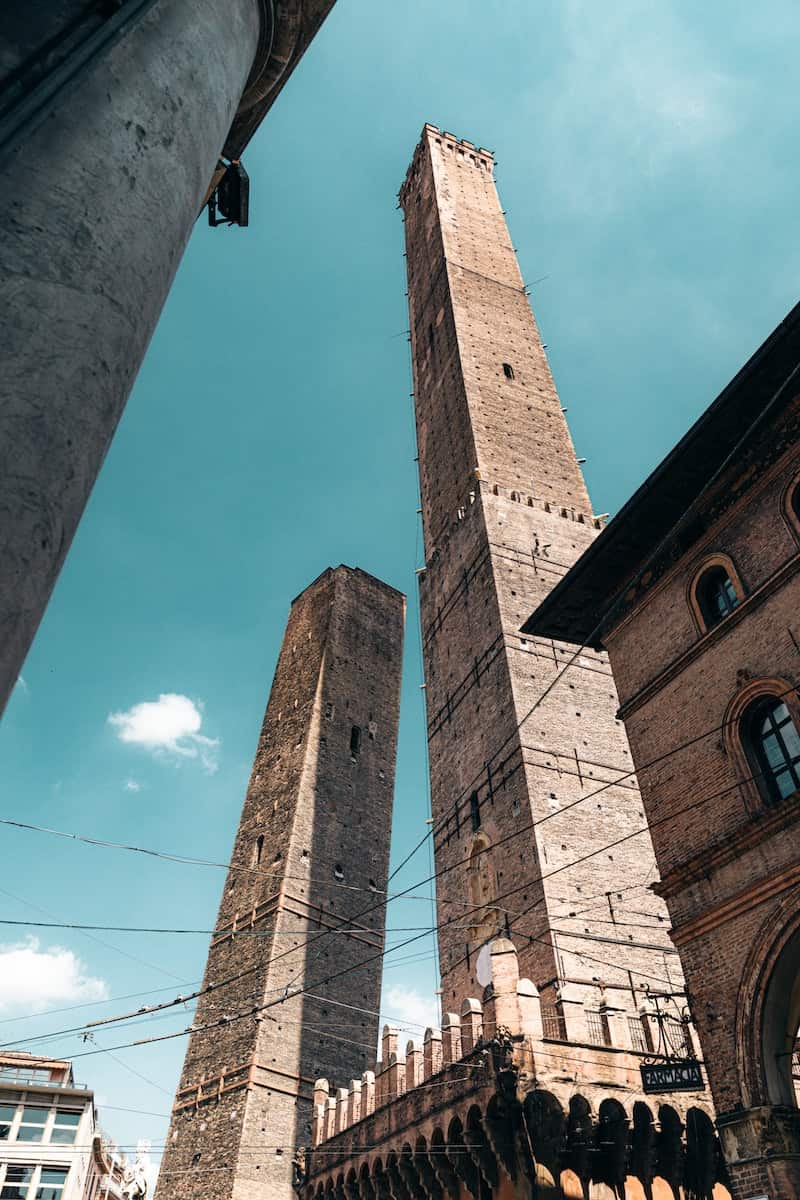 brown concrete tower of Torre degli Asinelli in Bologna under blue sky during daytime