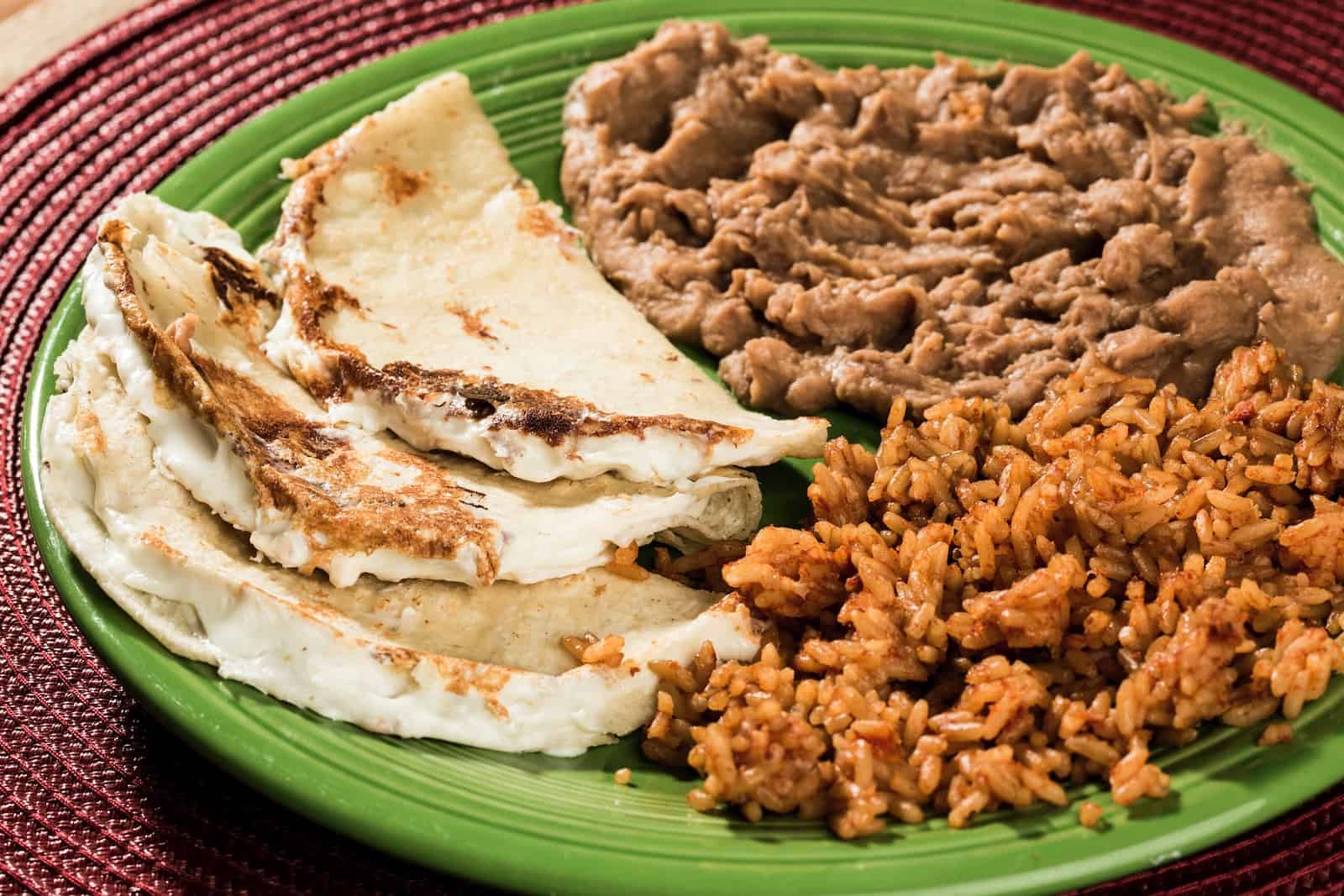 fried rice, beans, and mexican quesadilla on green ceramic plate