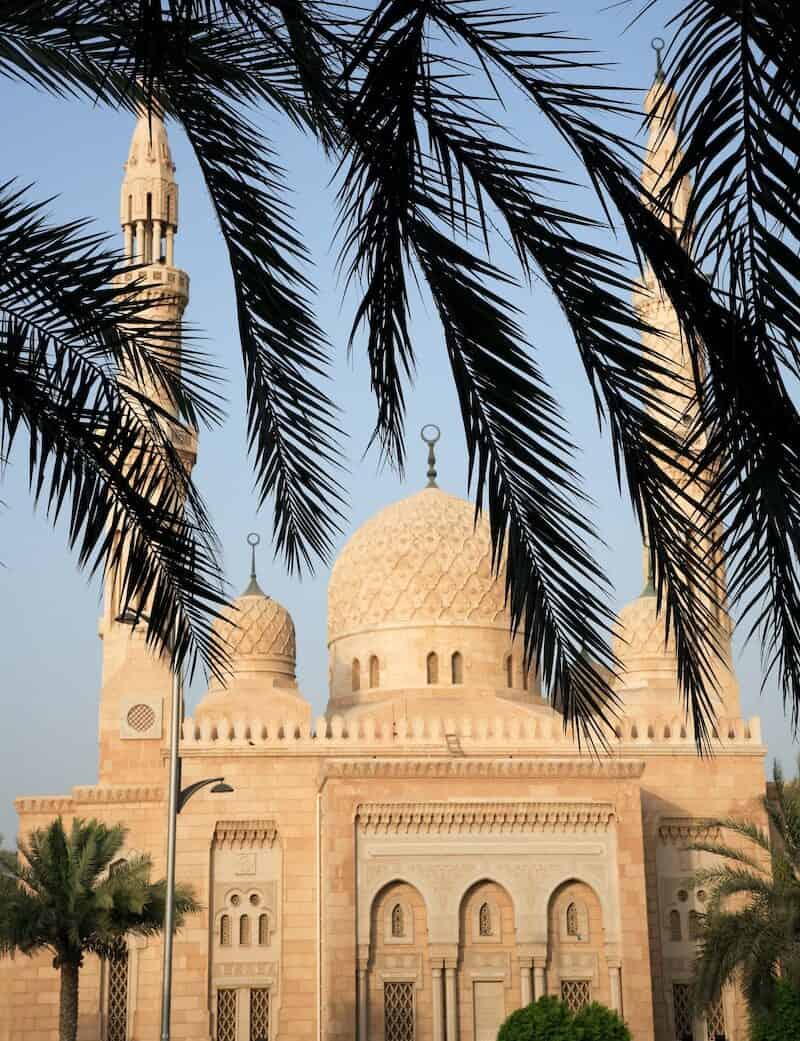 white concrete Jumeirah mosque near palm trees during daytime in Dubai