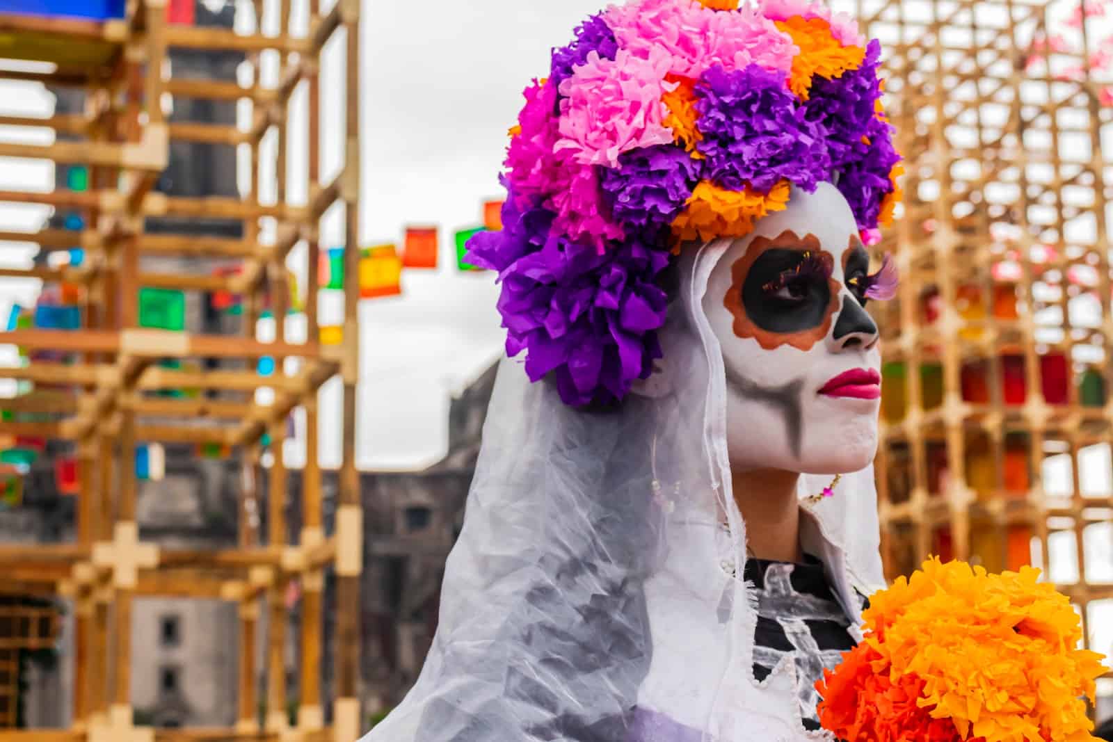 woman with calavera makeup wearing flower crown near city scaffolding