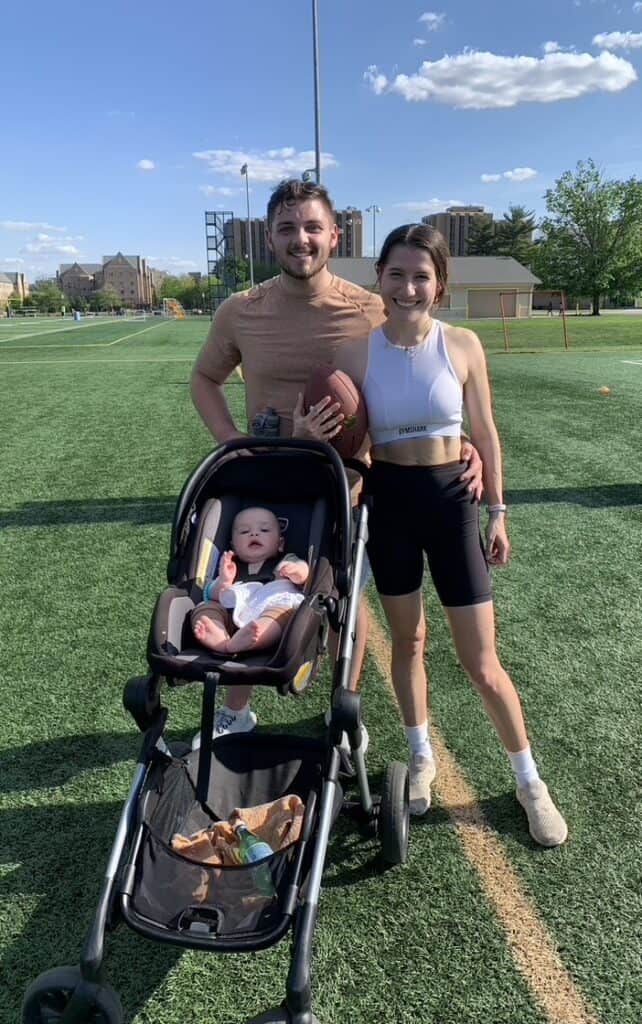 mom and dad on football field with baby in stroller