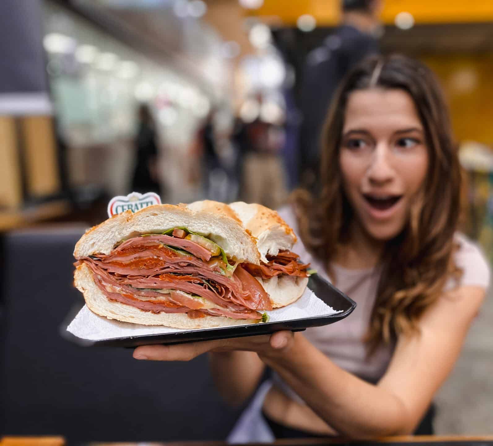 woman holding a huge meat sandwich near her face