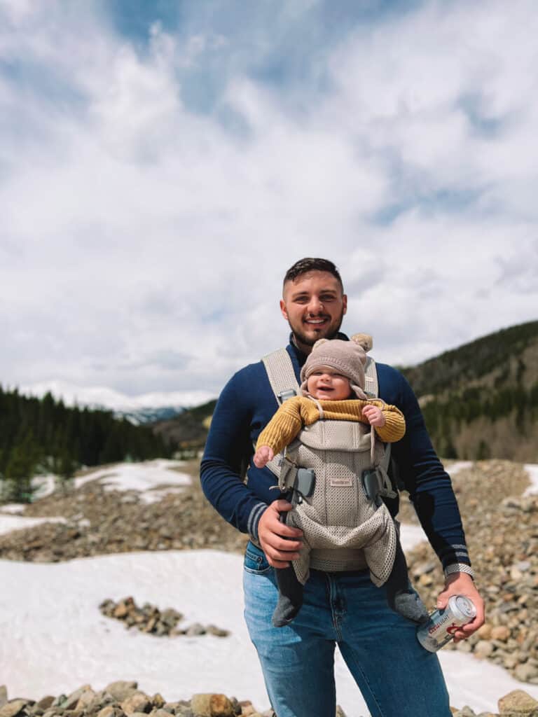 father with baby son strapped to his chest admiring the rocky mountains