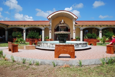 exterior of white tequila hacienda with fountain  in Mexico with terracotta roof