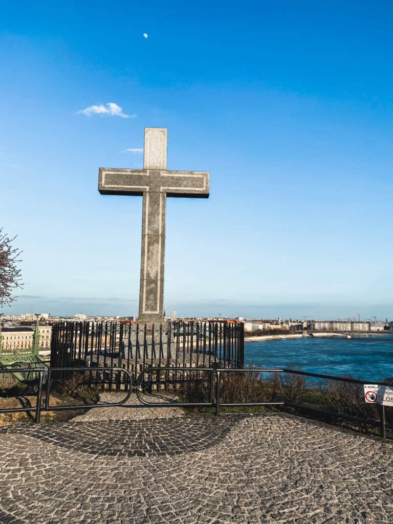 concrete cross overlooking river on bright day