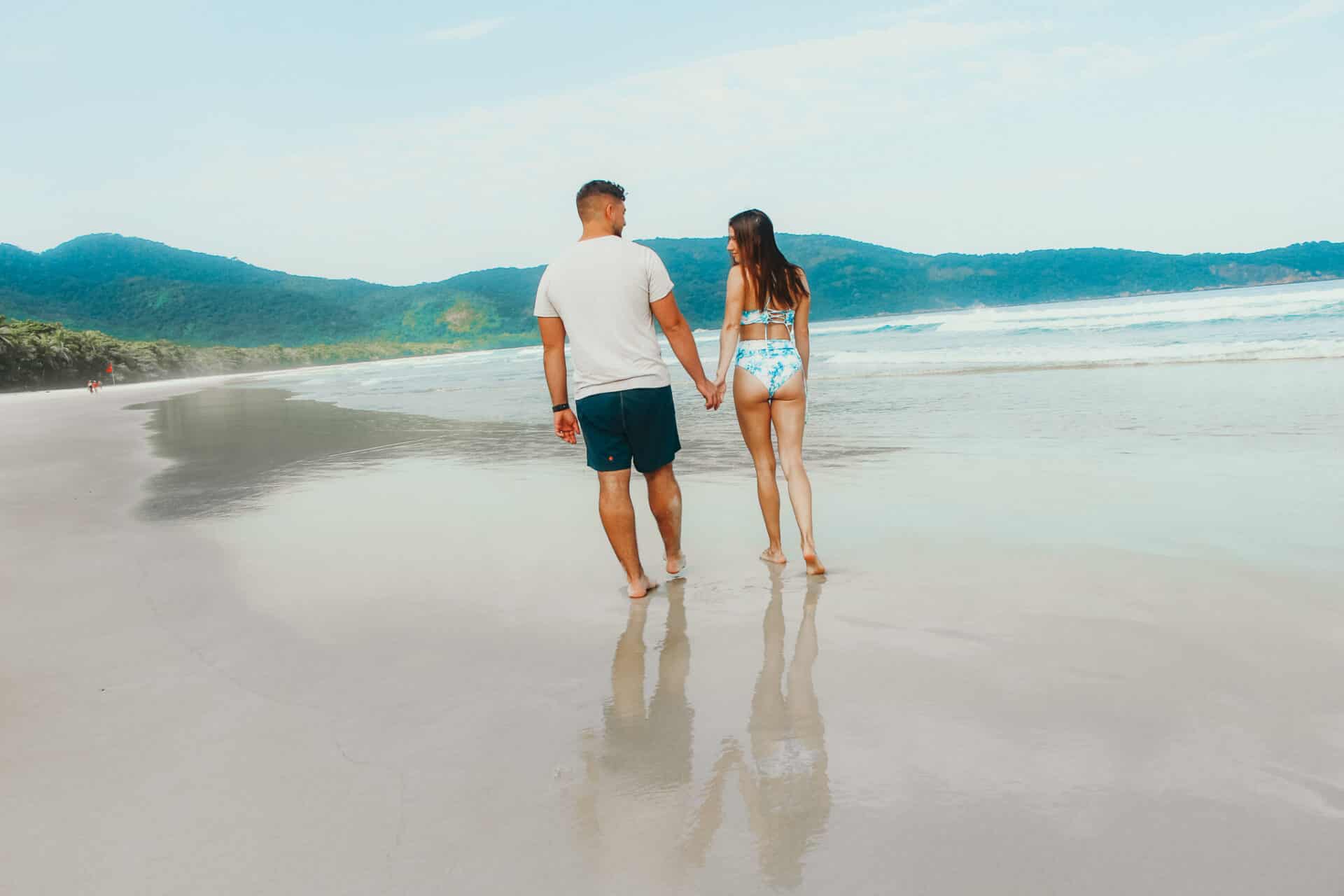 man and woman holding hands during walk on beach